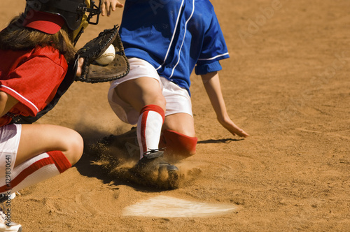 Female baseball player sliding into base with baseman in the foreground photo