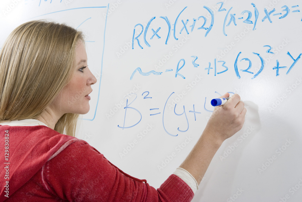 Young student solving mathematics problem on white board Young student solving mathematics problem on white board