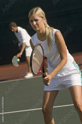 Man and woman playing doubles at the tennis court © moodboard