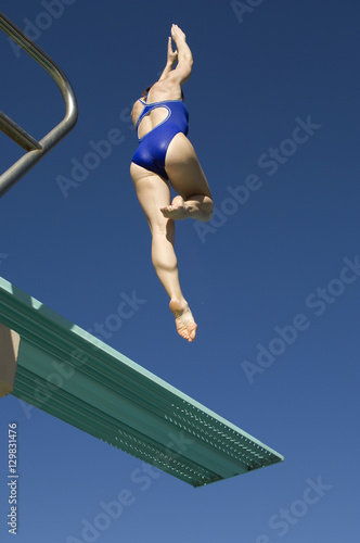 Rear view of a female swimmer diving of the springboard