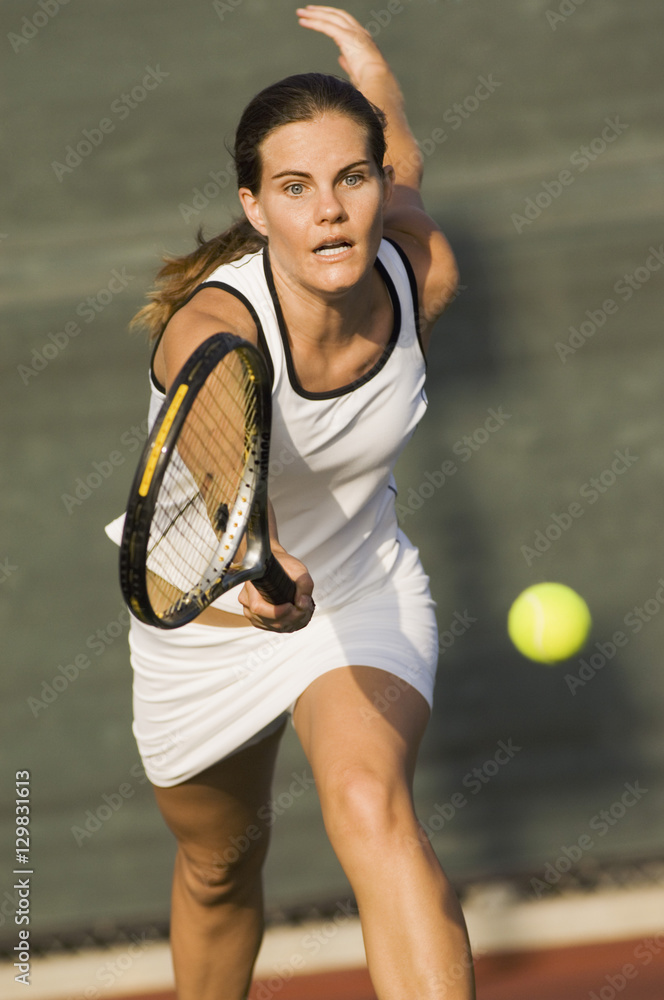 Sporty female tennis player running ahead for a shot on tennis court