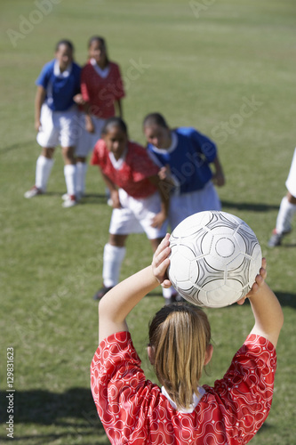 Rear View of a young woman ready to throw soccer ball towards team © moodboard