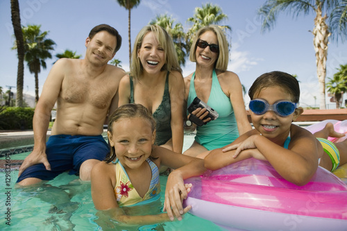 Portrait of smiling two girls with parents and grandmother in the swimming pool 