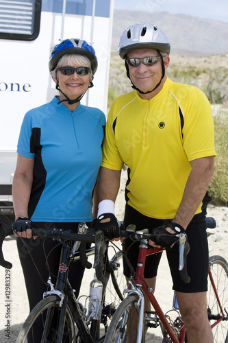 Portrait of a happy senior couple standing with their bicycles
