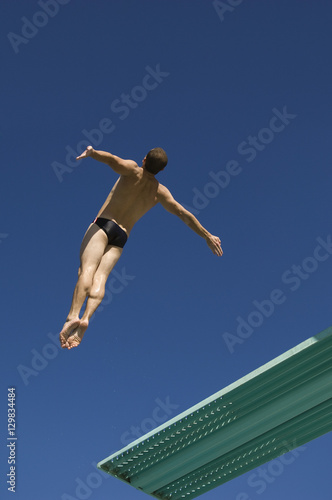 Low angle view of a male diver diving from springboard in midair