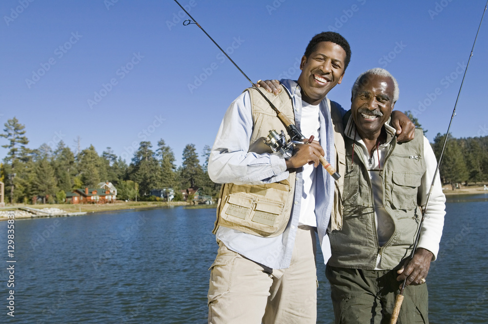 Portrait of happy senior man and adult son holding fishing rods by