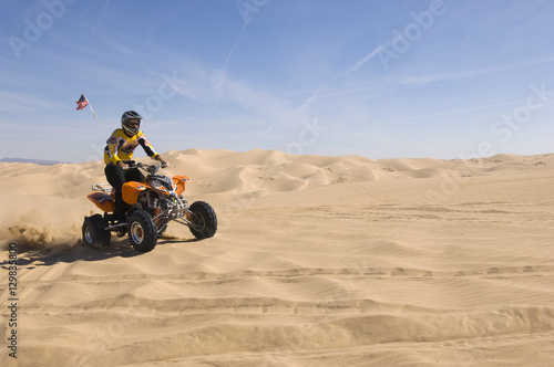 Young man riding quad bike in desert