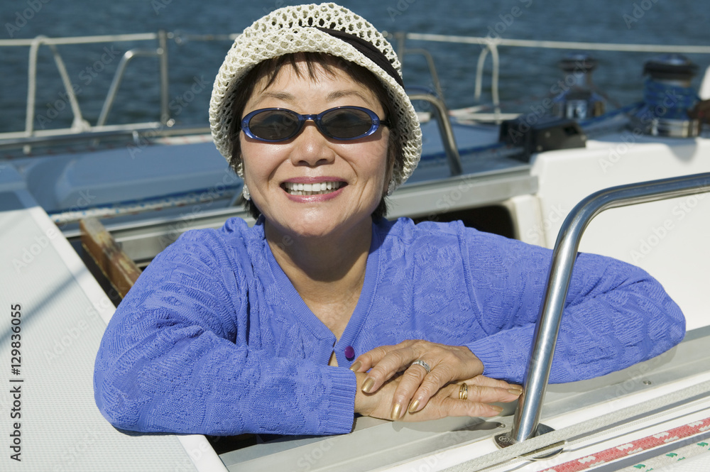 Woman wearing sunglasses on sailboat smiling (portrait)