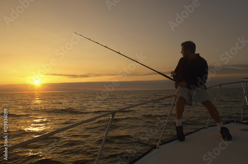 Silhouette image of young man fishing on yacht