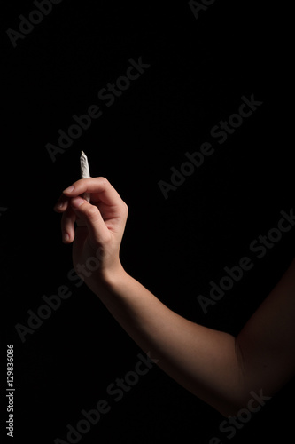 female hand with joint of marijuana on black background 