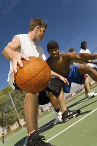Low angle view of young men playing basketball on court