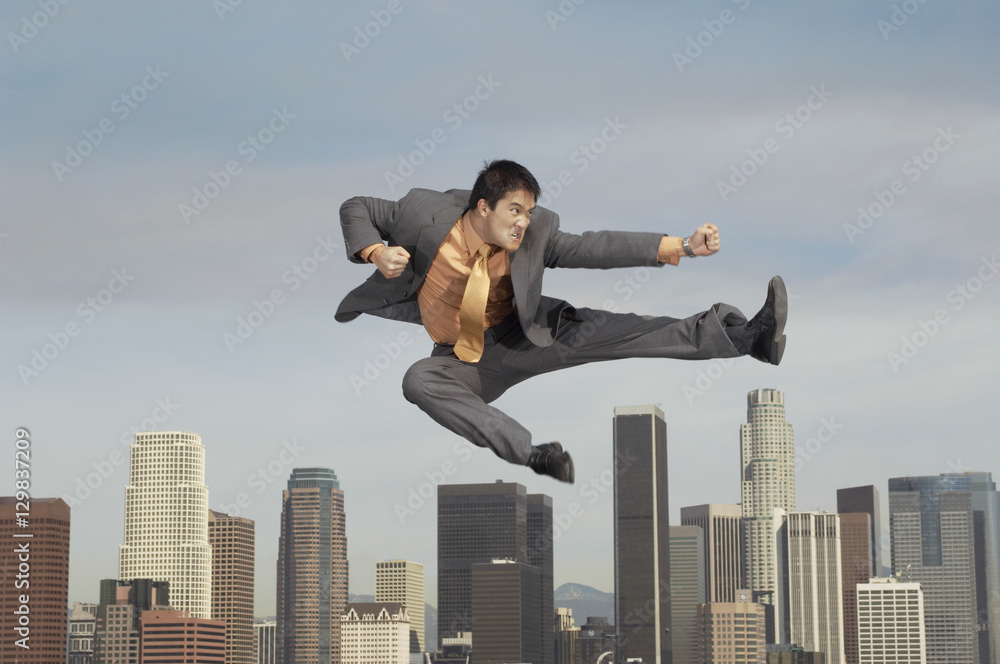 Full length of young businessman doing martial arts against cityscape Full length of young businessman doing martial arts against cityscape