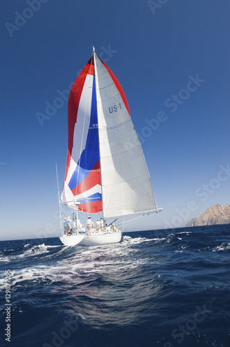 Rear shot of a yacht with colorful sail in the ocean against the clear sky