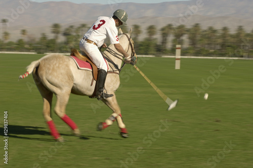 Blurred motion of polo player swinging at ball
