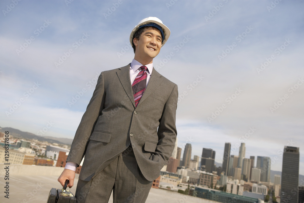 Male architect standing on building rooftop with hand in pocket Male architect standing on building rooftop with hand in pocket
