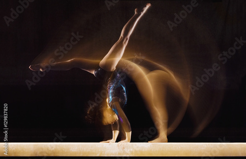 Multiple exposure image of female gymnast in motion on balance beam photo