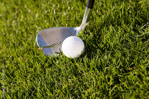 Closeup of a golf club and ball on grass