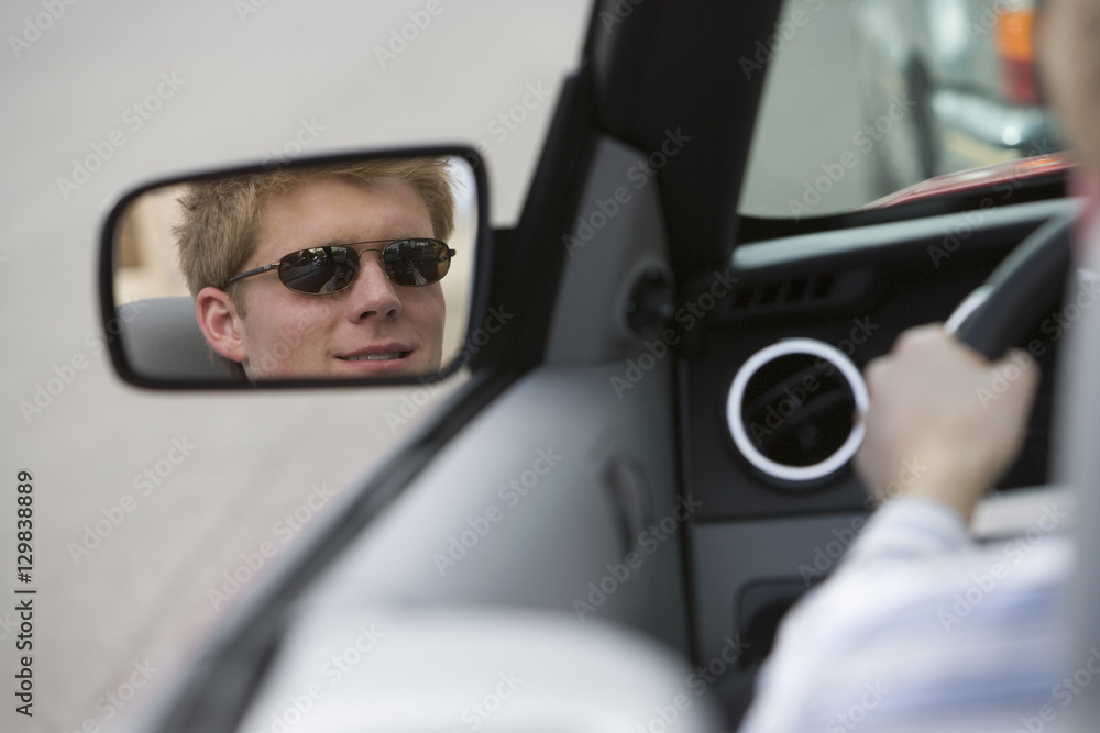Reflection of young man in side view mirror of car Reflection of young man in side view mirror of car