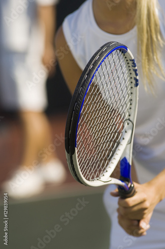 Closeup midsection of a tennis player with racket waiting for doubles partner to serve