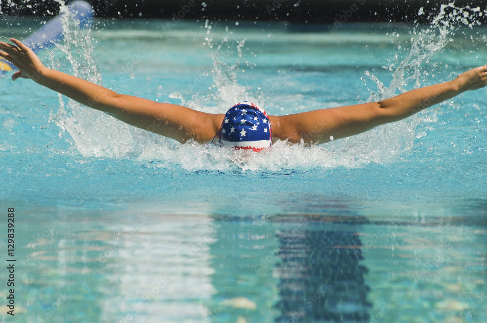 Female athlete performs a butterfly stroke during a swimming race