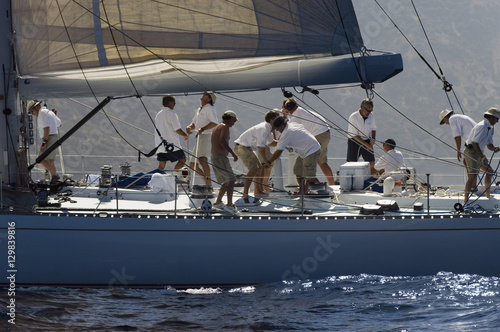 Side view of crew members working on sailboat Fototapeta