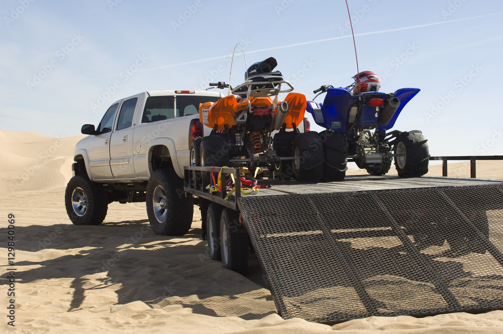 Quad bikes on trailer behind pickup truck in desert - obrazy, fototapety, plakaty 