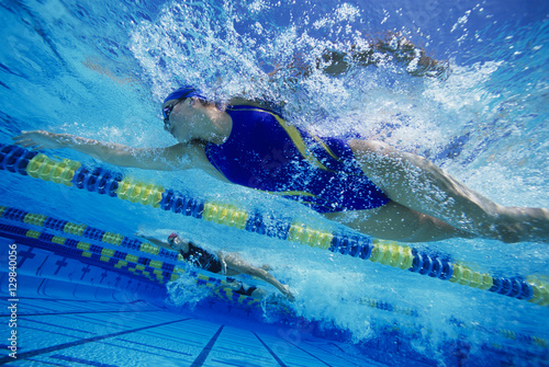 Low angle view of female swimmers gushing through water in pool photo