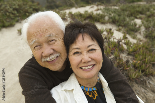 Mature couple embracing at beach smiling (portrait)