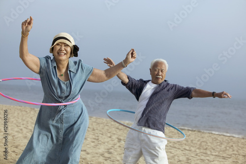 Couple with hula hoops on beach photo