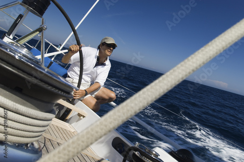 Sailor at the helm of a yacht in the ocean against blue sky
