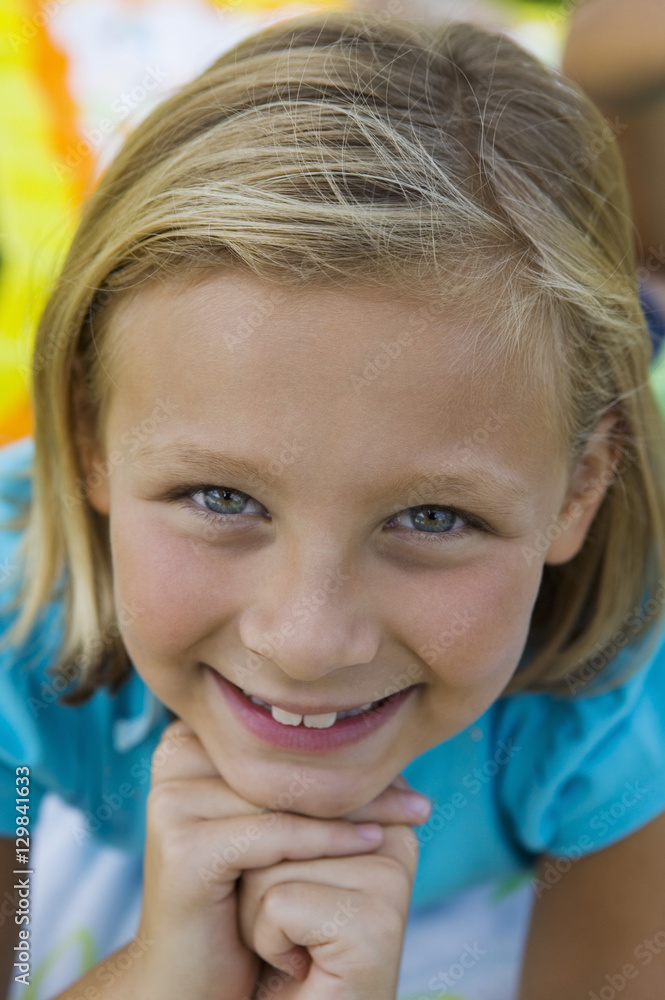 Closeup portrait of a beautiful little girl smiling with hands on chin