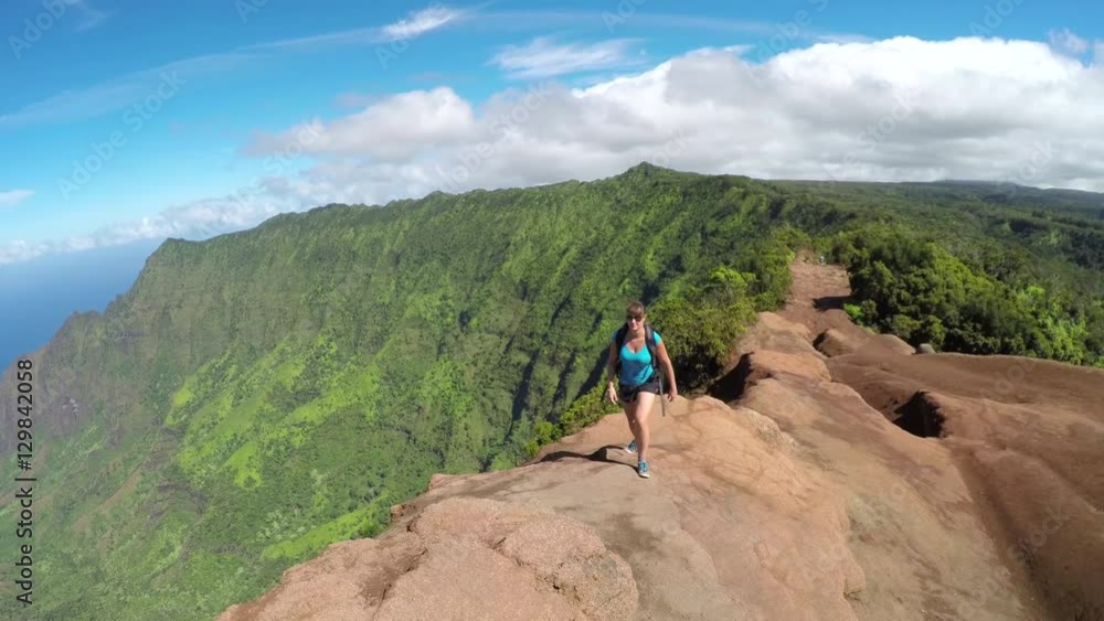Active young woman walking along the high mountain path with stunning ocean view Active young woman walking along the high mountain path with stunning ocean view