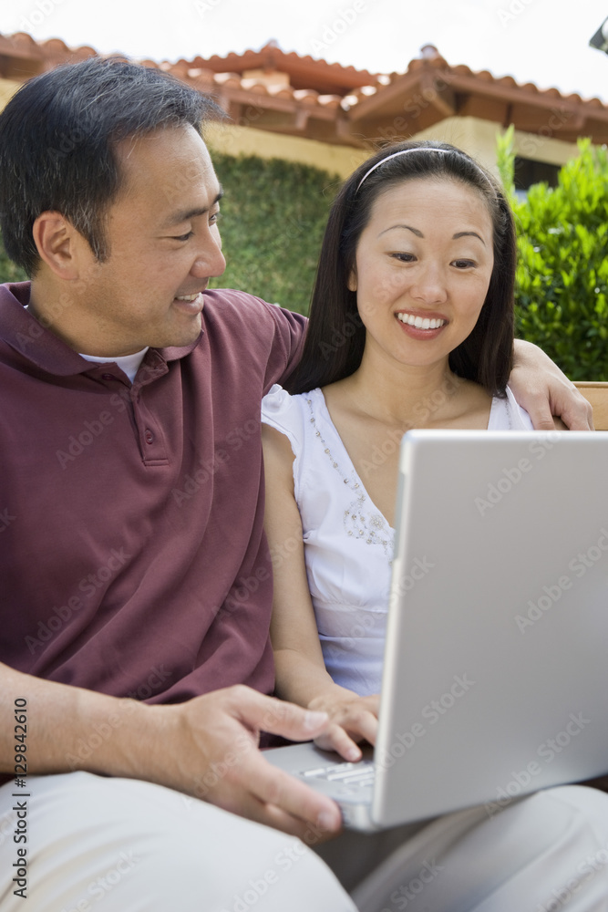 Happy mature Asian couple using laptop together Happy mature Asian couple using laptop together