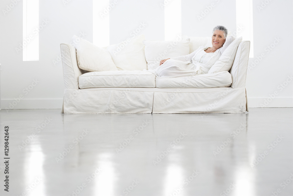Full length portrait of senior woman sitting on sofa in spacious room Full length portrait of senior woman sitting on sofa in spacious room