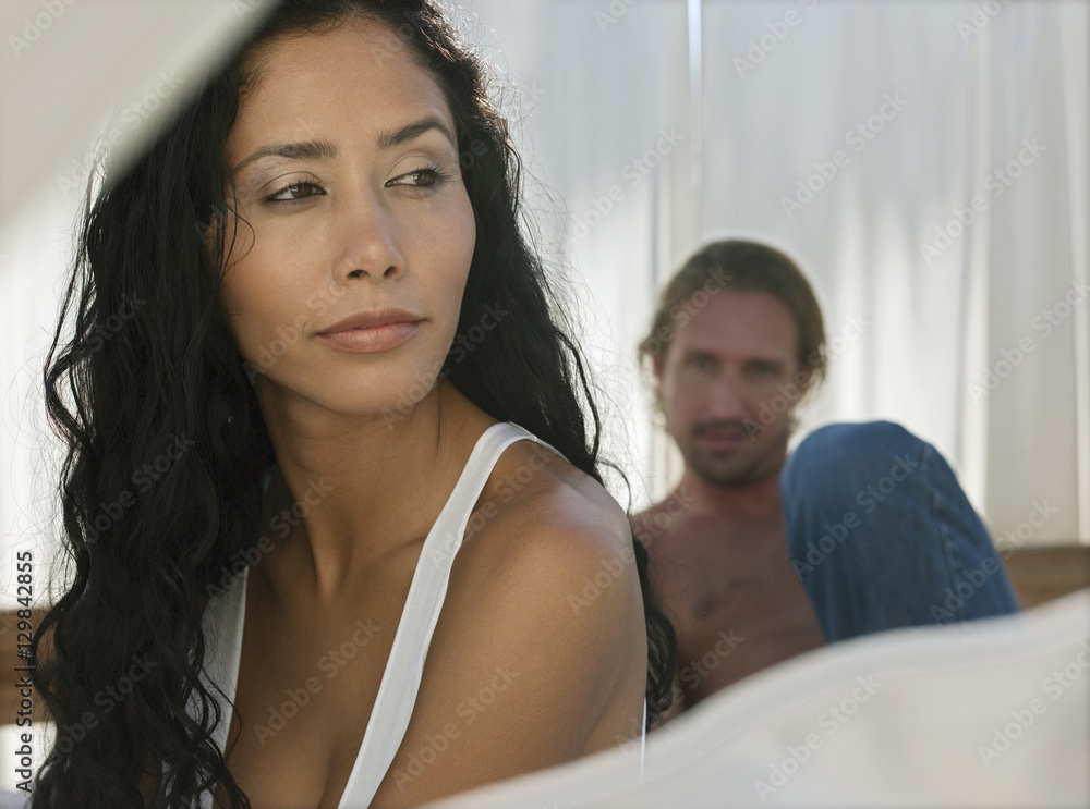 Beautiful young woman looking away with man in background