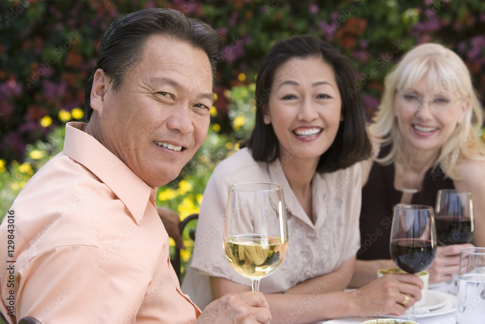 Portrait of happy senior man with female friends celebrating with wine Portrait of happy senior man with female friends celebrating with wine
