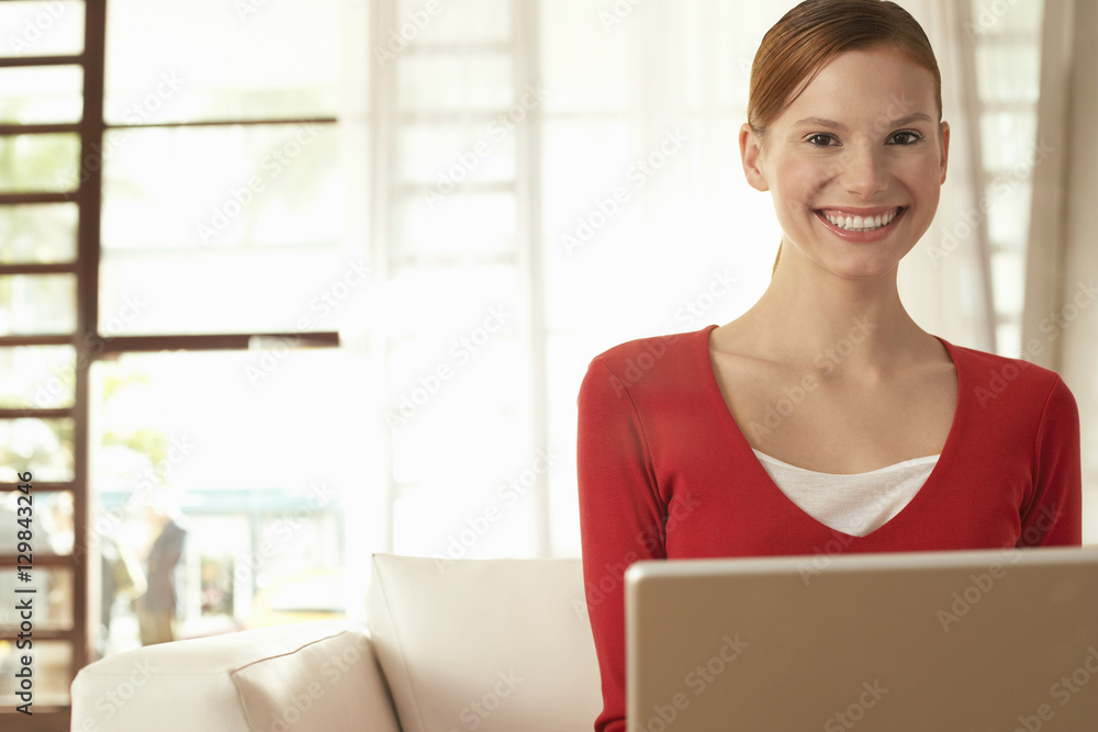 Portrait of happy young businesswoman with laptop sitting on chair in office lobby Portrait of happy young businesswoman with laptop sitting on chair in office lobby