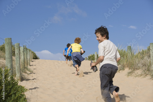 Rear view of boys running on sand