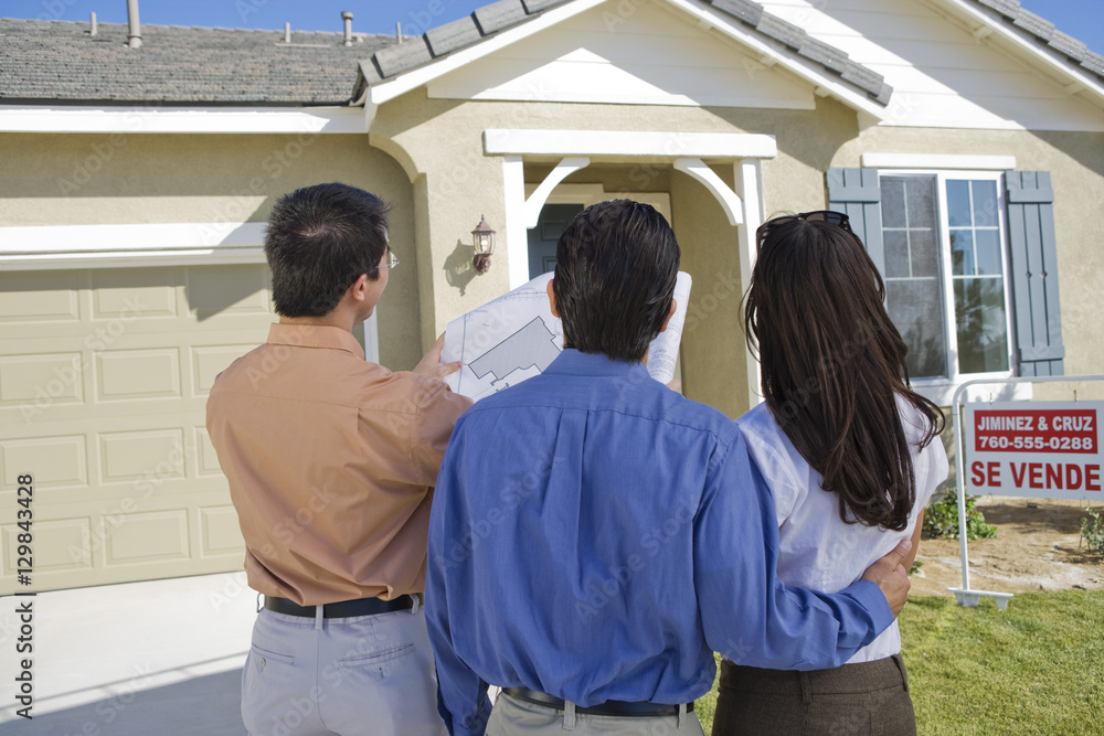 Fototapeta premium Rear view of couple with real estate agent explaining housing plan
