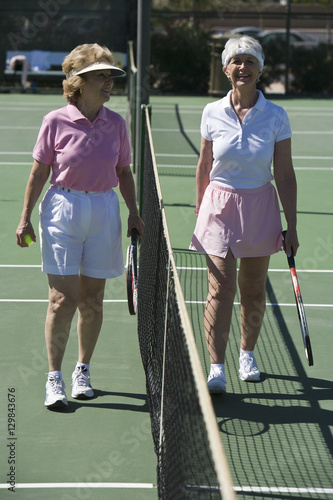 Full length of a senior women standing at net on tennis court © moodboard