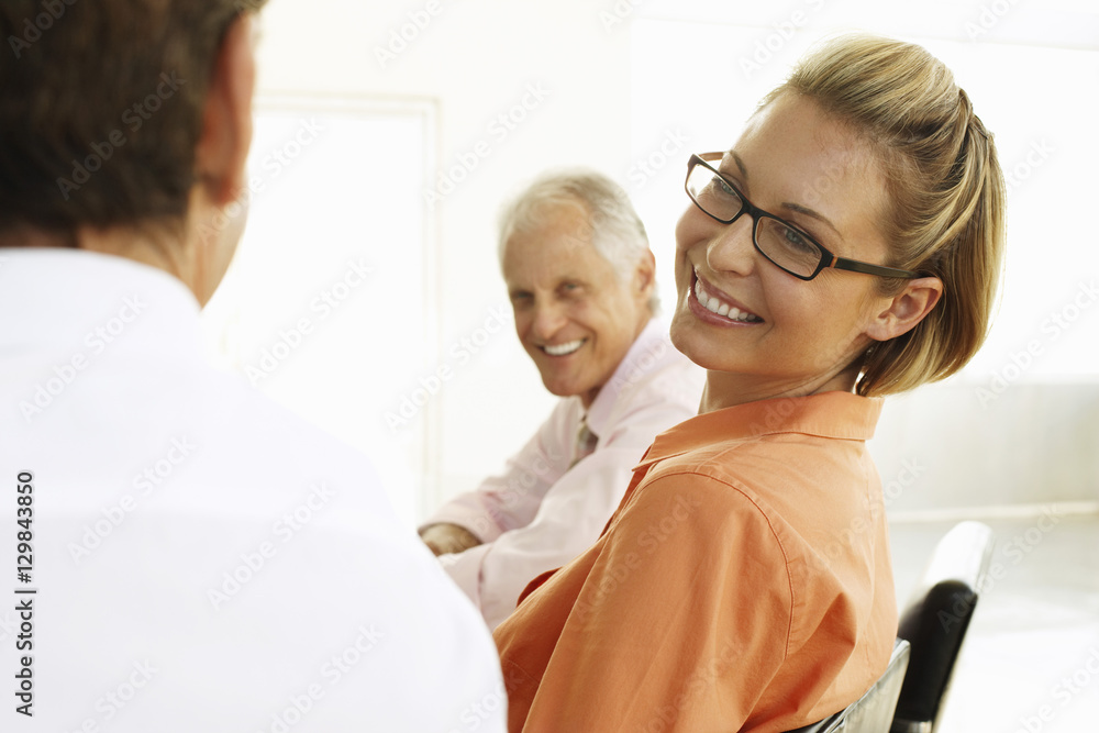 Smiling young businesswoman with male colleagues in conference room Smiling young businesswoman with male colleagues in conference room