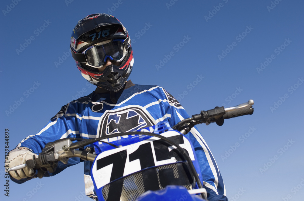Low angle of male off road motor biker against clear sky Low angle of male off road motor biker against clear sky