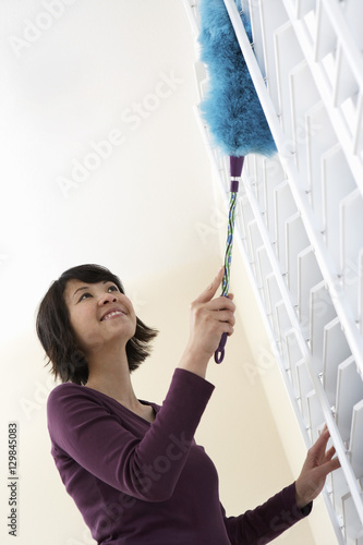 Wall Mural Low angle view of a smiling Asian woman dusting window