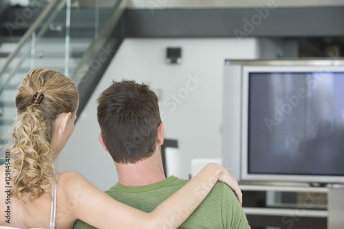 Rear view of young couple watching TV at home