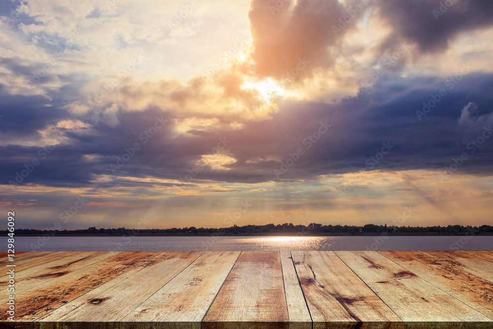 Wooden table at riverside on beautiful sunset background.