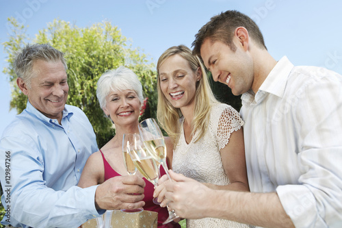 Happy young and senior couple toasting champagne flutes outdoors