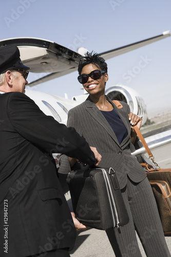 Fotografija Senior driver taking briefcase from businesswoman with airplane in the backgroun