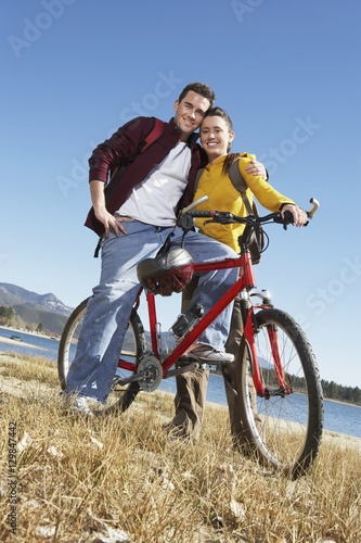 Full length portrait of happy Caucasian couple standing together with a bicycle