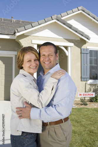 Portrait of happy mature couple embracing in front of new house