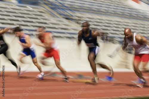 Blurred motion of male athletes racing in stadium